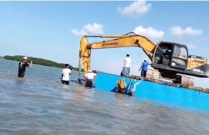 Warga kampung Tapakerbau tampak berusaha mengusir eskavator yang sedang beraktivitas di laut. [Tangkapan layar]
