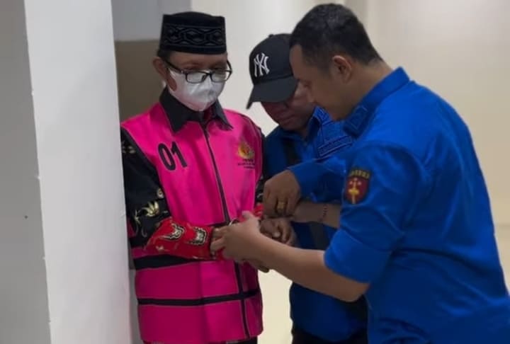 Tim Kejari Sumenep memborgol kedua tangan Kades Pragaan Daya, Imrah, sebelum digiring ke mobil tahanan.